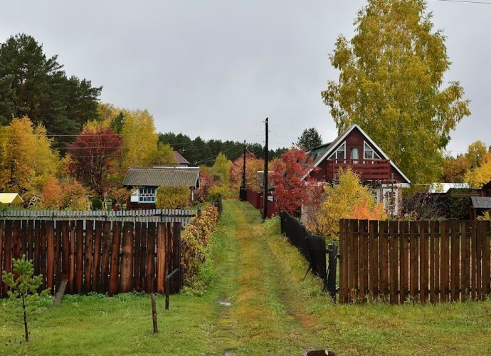 a fenced in yard with a house and trees in the background